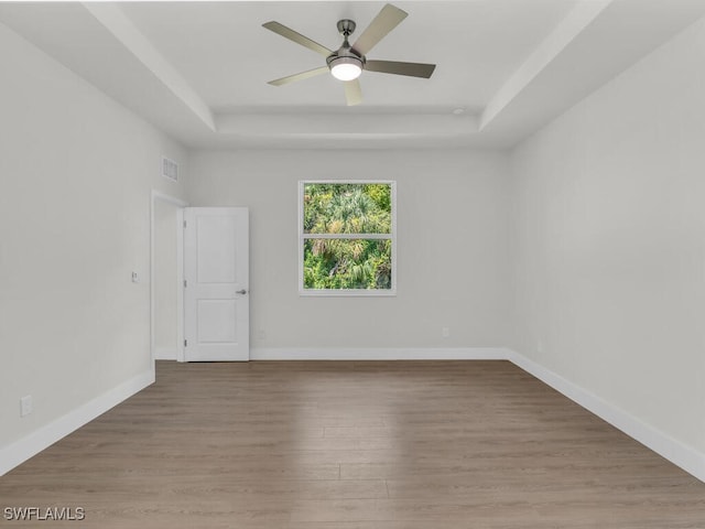 spare room featuring a tray ceiling, light hardwood / wood-style floors, and ceiling fan