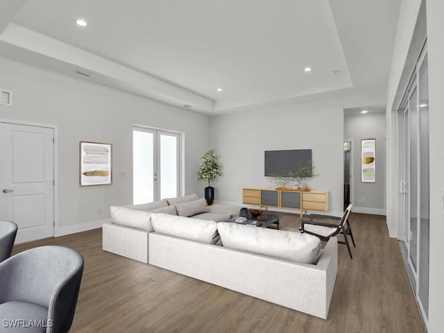 living room with hardwood / wood-style floors and a raised ceiling