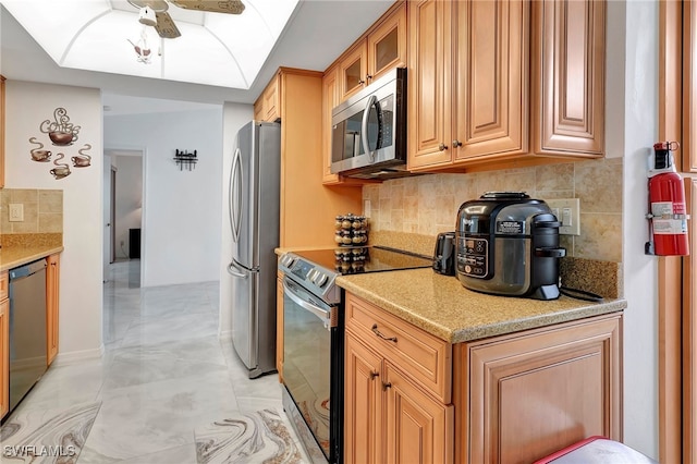 kitchen featuring ceiling fan, light tile patterned floors, appliances with stainless steel finishes, and decorative backsplash