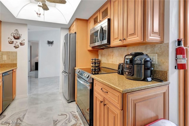 kitchen with ceiling fan, decorative backsplash, appliances with stainless steel finishes, and light stone counters