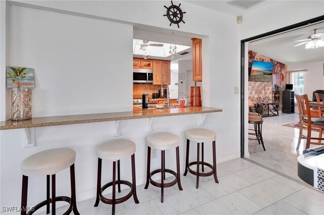 kitchen featuring ceiling fan, backsplash, pendant lighting, and light tile patterned floors