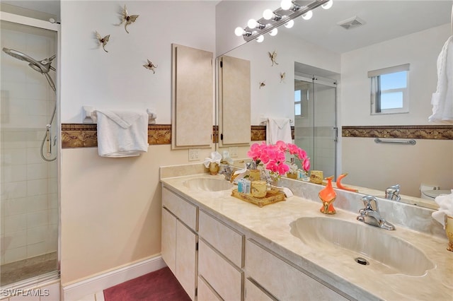 bathroom with double sink vanity, toilet, and tiled shower