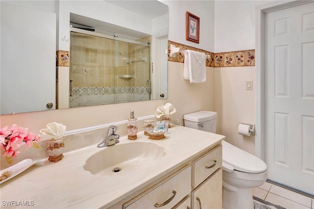 bathroom featuring toilet, tile patterned flooring, vanity, and a shower with door