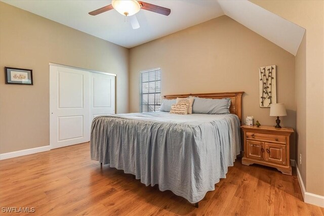 bedroom with light hardwood / wood-style flooring, ceiling fan, a closet, and lofted ceiling