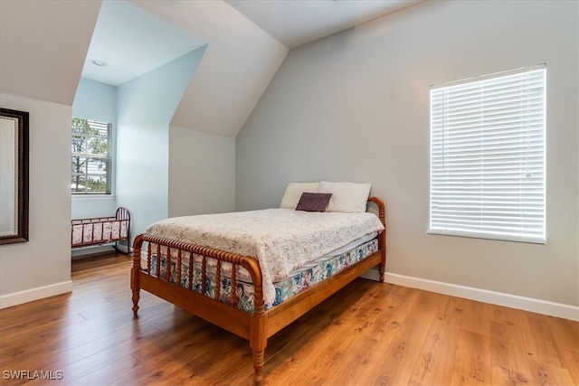 bedroom with light hardwood / wood-style floors and lofted ceiling