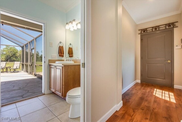 bathroom featuring wood-type flooring, vanity, crown molding, toilet, and lofted ceiling