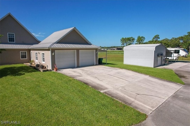 view of front of house with an attached garage, driveway, metal roof, and a front yard