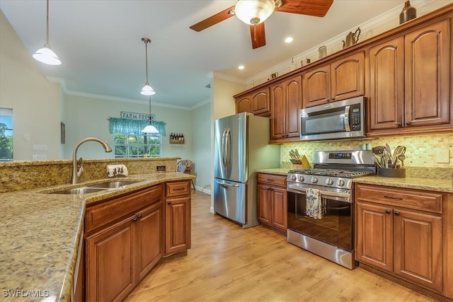 kitchen featuring sink, stainless steel appliances, hanging light fixtures, and light hardwood / wood-style flooring