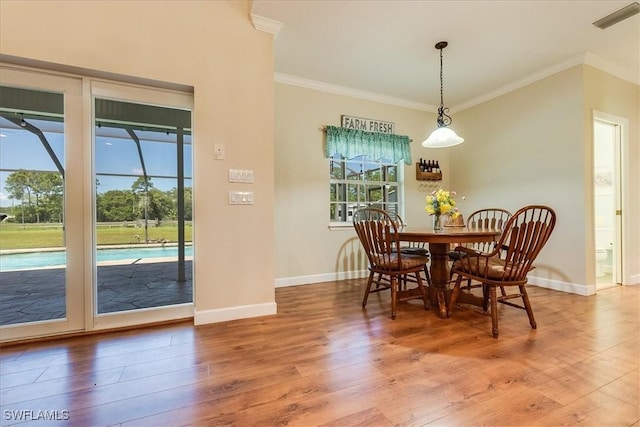 dining space featuring visible vents, crown molding, baseboards, and wood finished floors