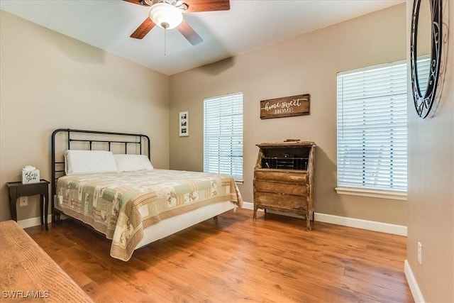 bedroom featuring a ceiling fan, baseboards, and wood finished floors