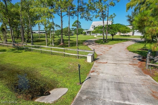 view of home's community featuring a yard, driveway, and fence