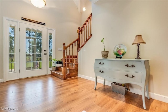 foyer with stairs, light wood-type flooring, a wealth of natural light, and baseboards