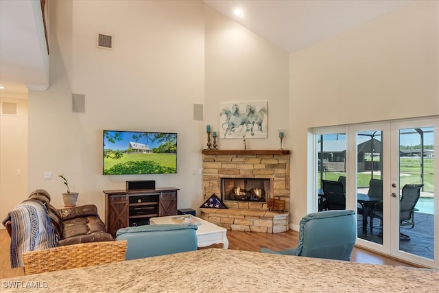 living room with a fireplace, high vaulted ceiling, hardwood / wood-style flooring, and french doors