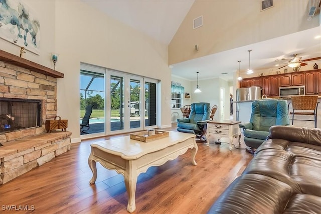 living area with visible vents, a stone fireplace, and light wood finished floors