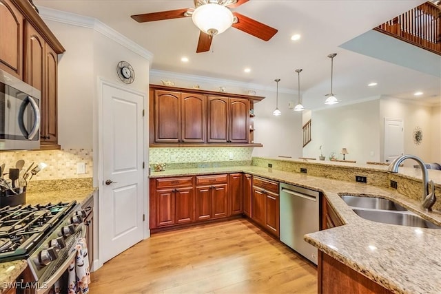 kitchen featuring light stone counters, hanging light fixtures, a peninsula, stainless steel appliances, and a sink