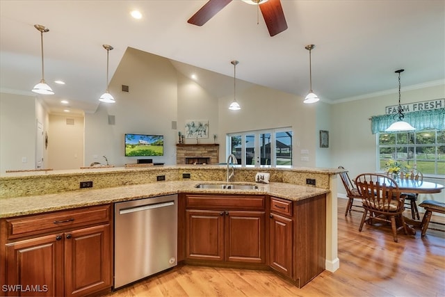 kitchen featuring sink, light stone countertops, light hardwood / wood-style floors, stainless steel dishwasher, and pendant lighting