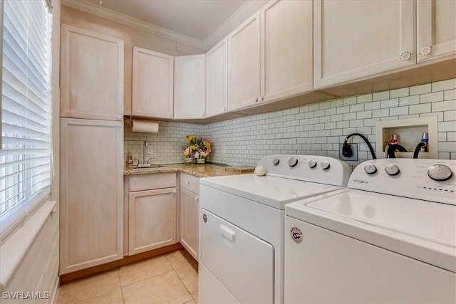 washroom featuring cabinet space, light tile patterned floors, washer and clothes dryer, ornamental molding, and a sink