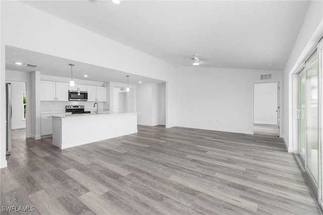 unfurnished living room featuring light wood-style floors, visible vents, ceiling fan, and a sink