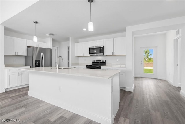 kitchen featuring white cabinets, appliances with stainless steel finishes, light countertops, and a sink