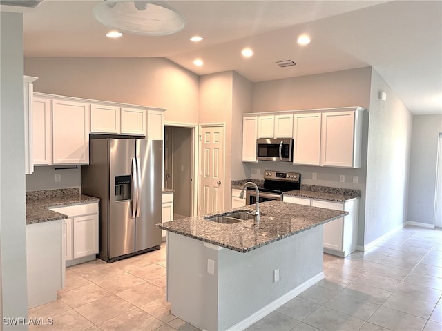 kitchen featuring visible vents, white cabinets, dark stone counters, stainless steel appliances, and a sink