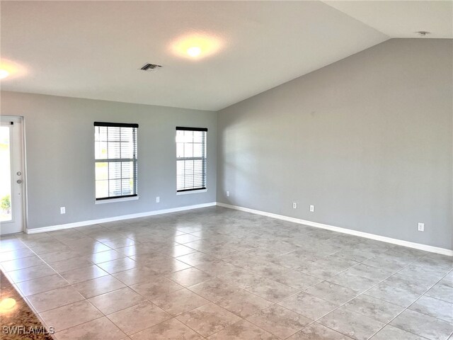 spare room with light tile patterned floors and vaulted ceiling