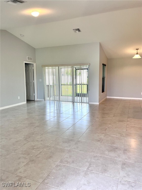 spare room with light tile patterned floors and vaulted ceiling