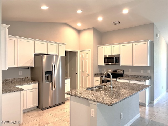 kitchen featuring an island with sink, vaulted ceiling, white cabinetry, light tile patterned floors, and stainless steel appliances