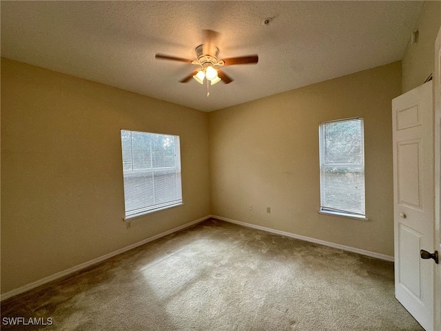 empty room featuring a textured ceiling, light colored carpet, and ceiling fan