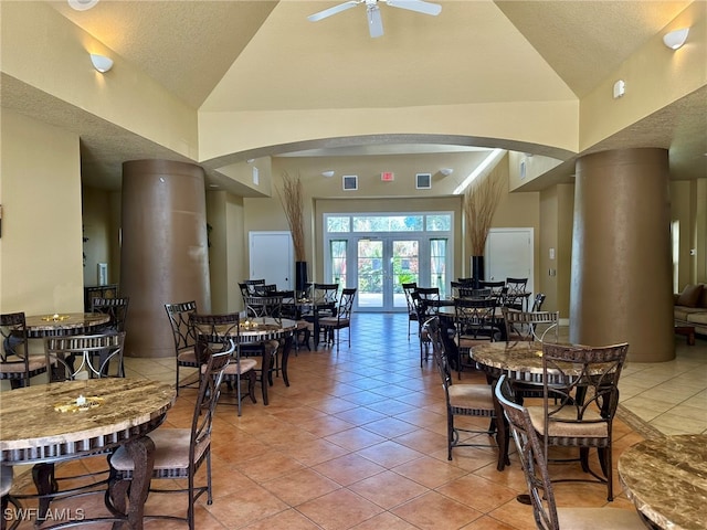 dining room featuring vaulted ceiling, light tile patterned flooring, a textured ceiling, and ceiling fan