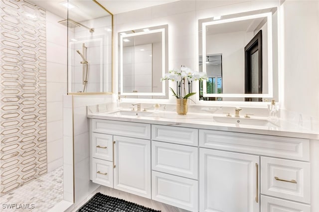 bathroom with a tile shower and double vanity