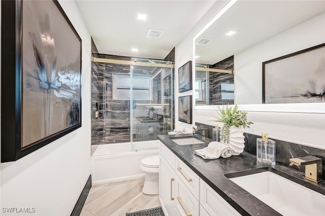 bathroom featuring toilet, shower / bath combination with glass door, visible vents, and a sink