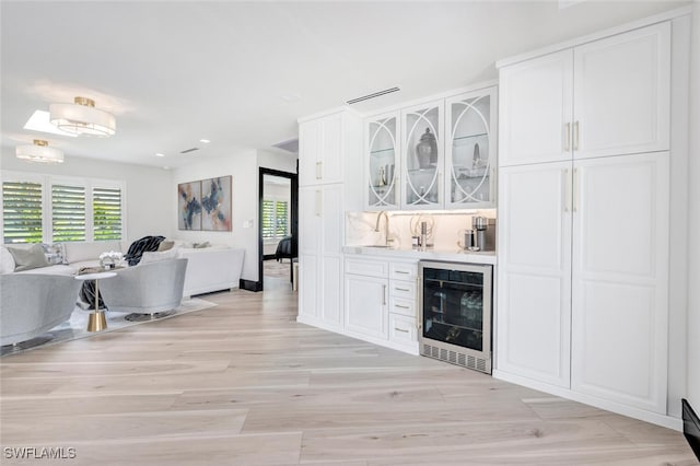 interior space with wine cooler, sink, and light hardwood / wood-style floors