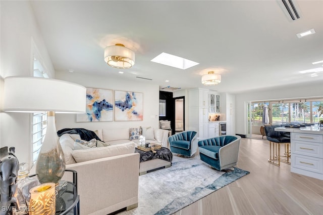 living room featuring a skylight and light hardwood / wood-style floors