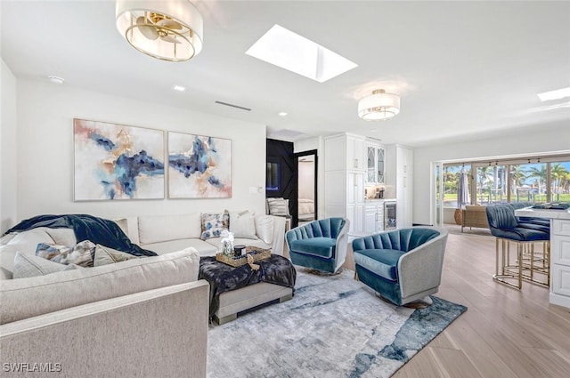 living area featuring a skylight, visible vents, and wood finished floors