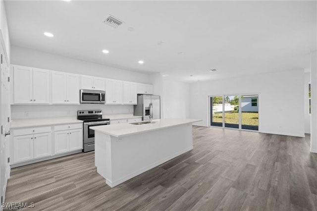 kitchen featuring a center island with sink, white cabinets, stainless steel appliances, and light hardwood / wood-style flooring