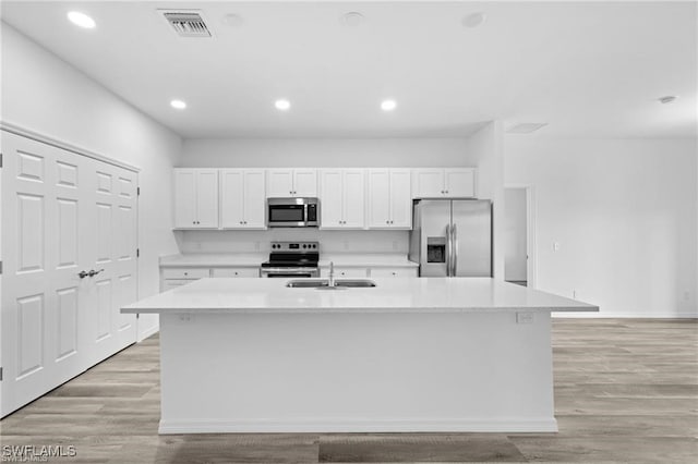 kitchen with sink, light hardwood / wood-style floors, a kitchen island with sink, white cabinets, and appliances with stainless steel finishes