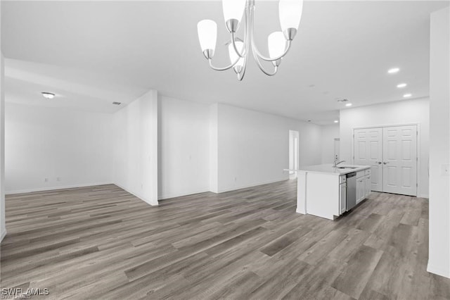 unfurnished living room with a notable chandelier, sink, and dark wood-type flooring