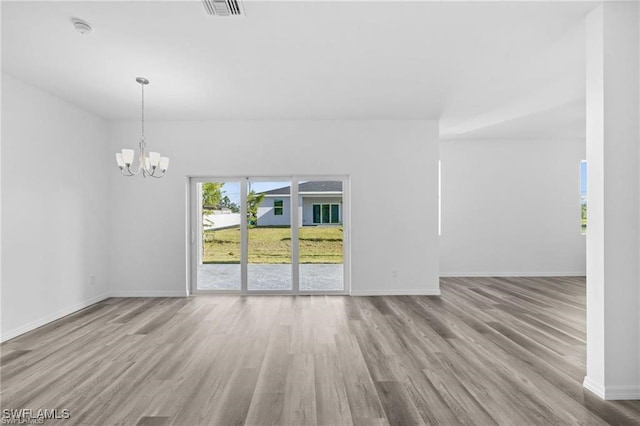 empty room with wood-type flooring and an inviting chandelier