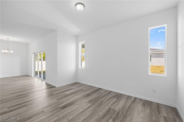 unfurnished room with wood-type flooring and a notable chandelier