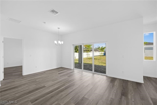 spare room featuring a chandelier and dark wood-type flooring