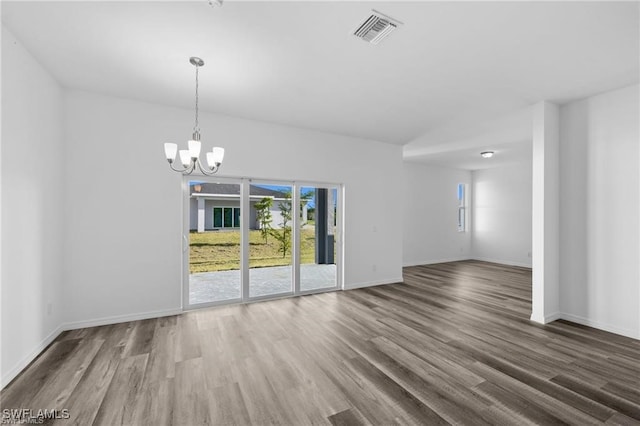 spare room with hardwood / wood-style flooring and a chandelier