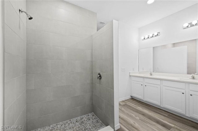 bathroom featuring tiled shower, wood-type flooring, and vanity