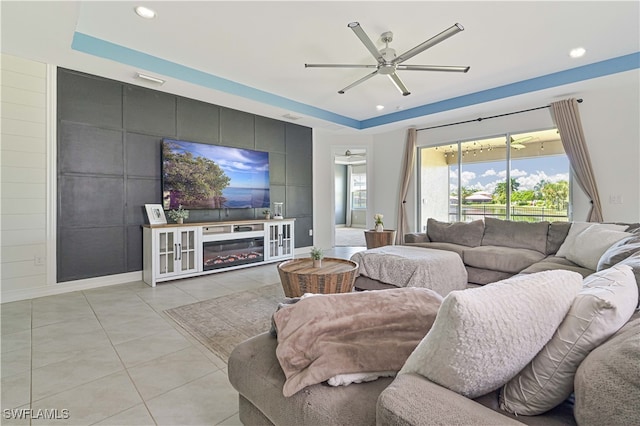 tiled living room featuring a tray ceiling and ceiling fan