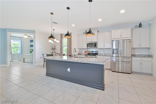 kitchen featuring backsplash, white cabinets, appliances with stainless steel finishes, light stone countertops, and light tile patterned flooring