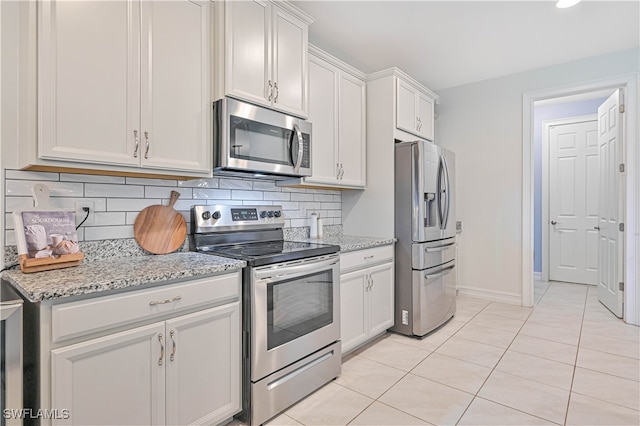 kitchen featuring light tile patterned floors, light stone counters, tasteful backsplash, white cabinetry, and stainless steel appliances