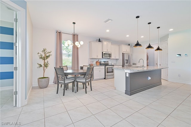 kitchen with appliances with stainless steel finishes, white cabinetry, light tile patterned floors, and backsplash