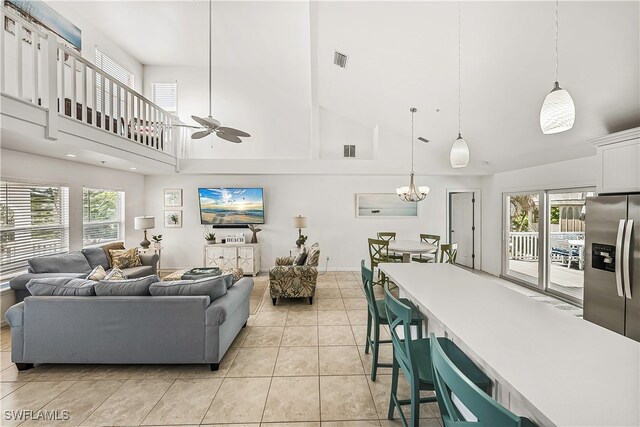 tiled living room featuring ceiling fan with notable chandelier and high vaulted ceiling