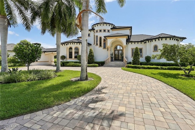 mediterranean / spanish-style house featuring a garage, a front yard, and french doors