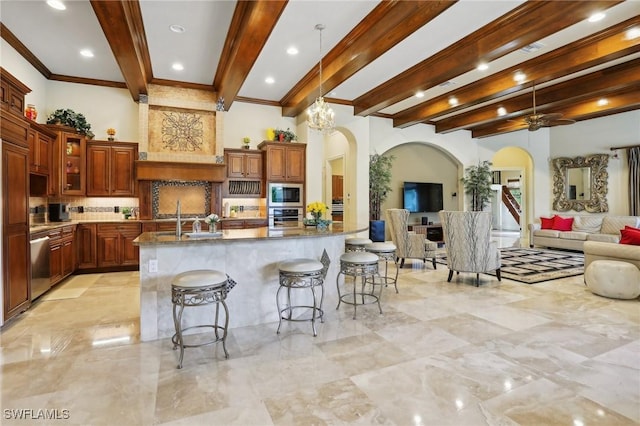 kitchen with backsplash, a kitchen bar, dark stone counters, a kitchen island with sink, and stainless steel appliances