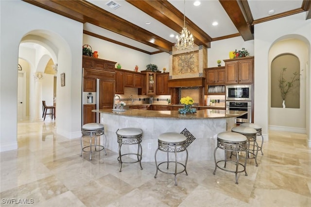 kitchen with a spacious island, stainless steel appliances, a kitchen bar, and dark stone countertops